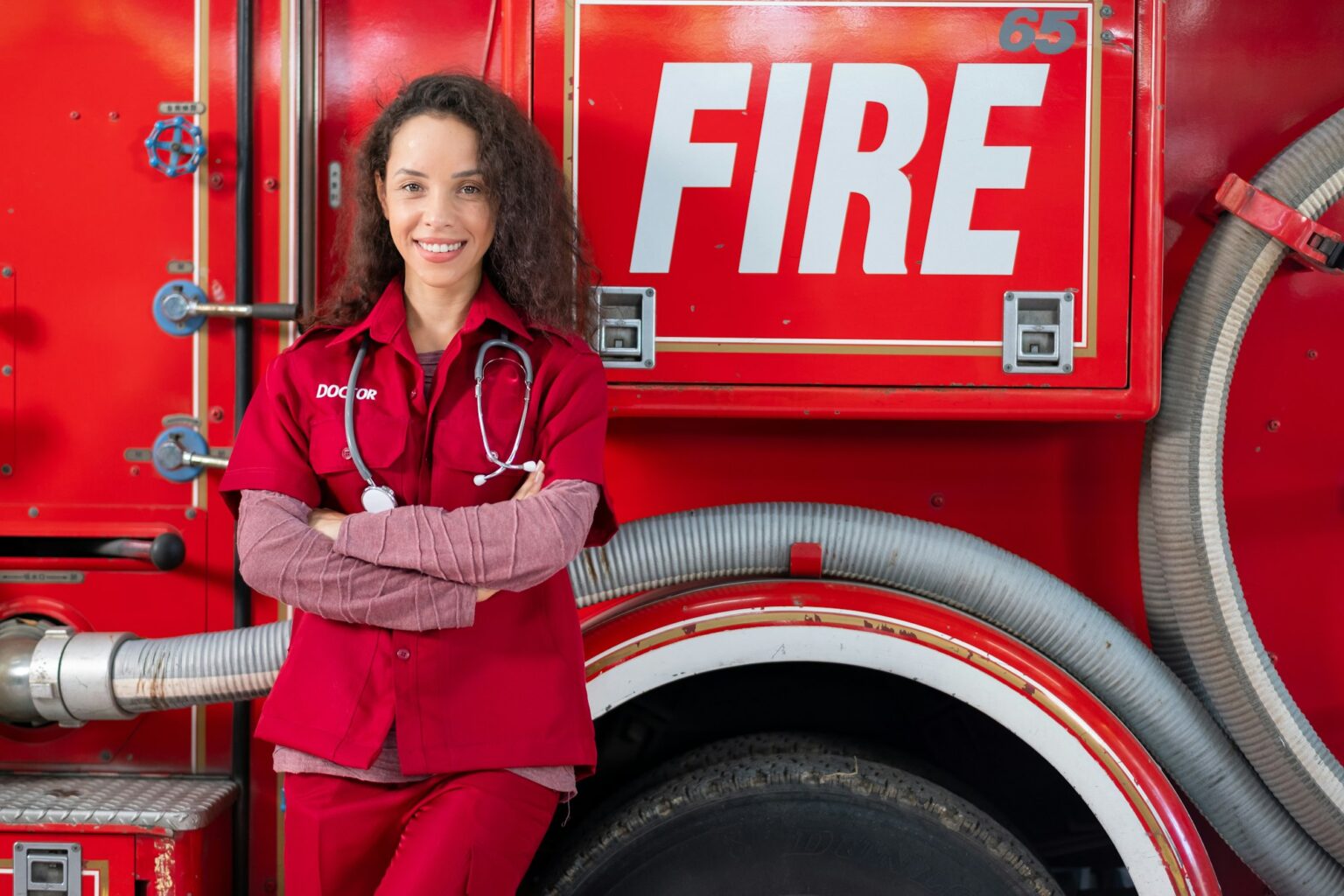 Beautiful emergency doctor woman stand and lean fire truck with smiling